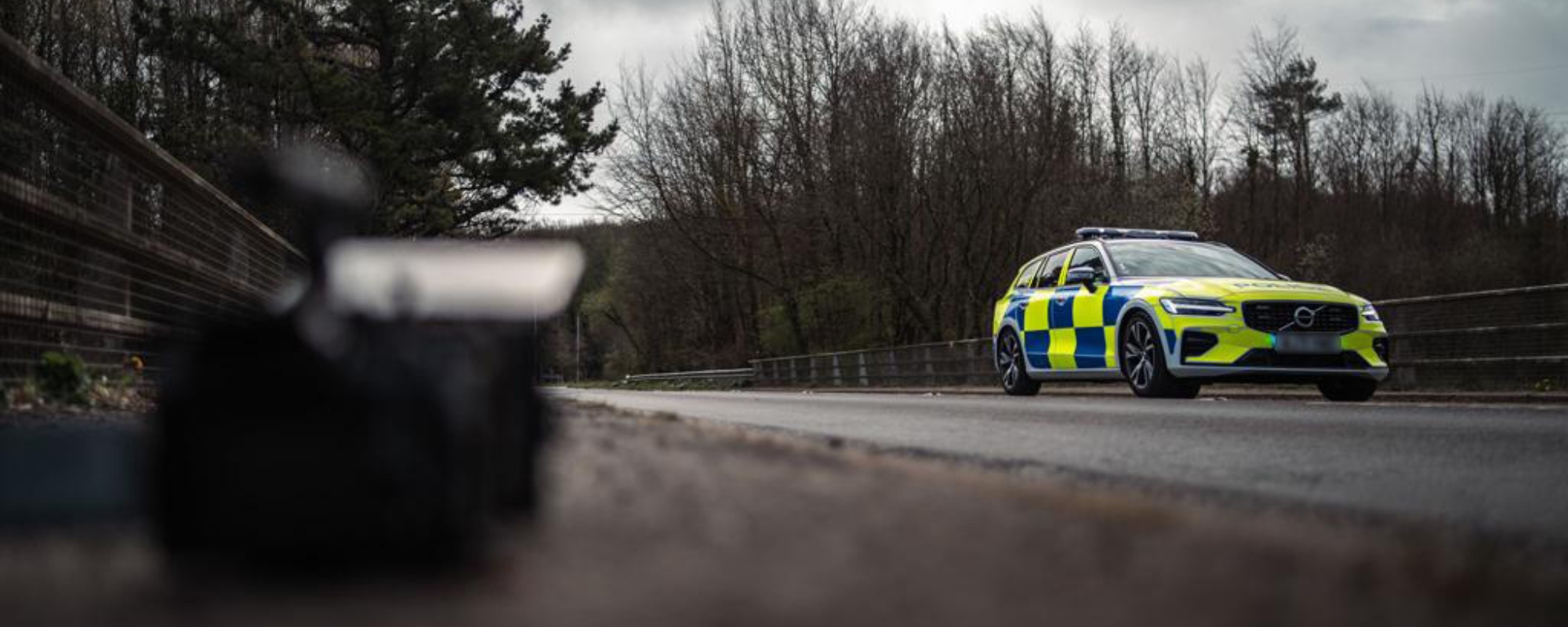 A police car driving along a country road on a cloudy day
